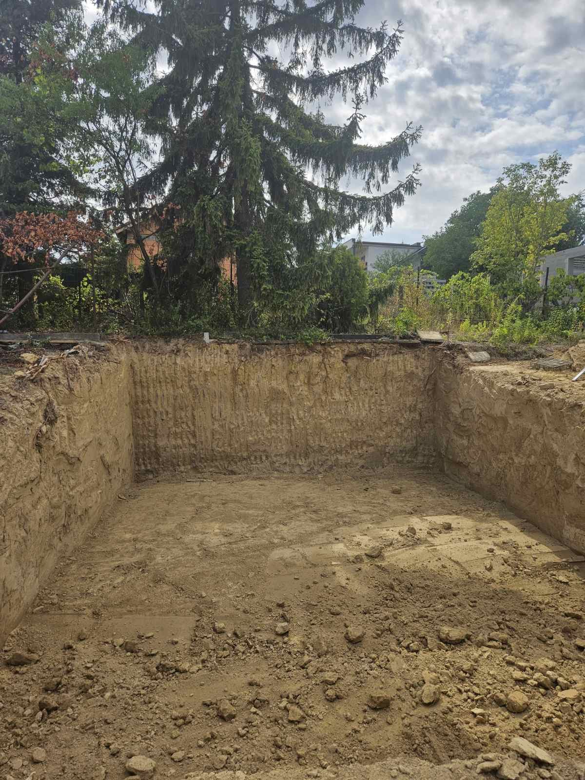Kiásott alapgödör egy telken, egyenes rézsűfalakkal