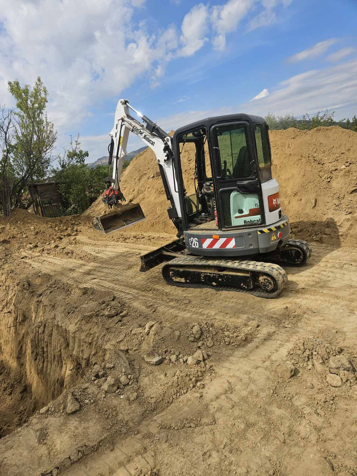 Bobcat E26 minikotró kitermelt földkupac mellett