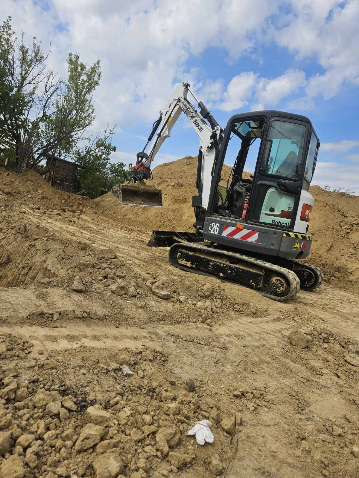 Bobcat minikotró földdepó előtt, gépi földmunka közben